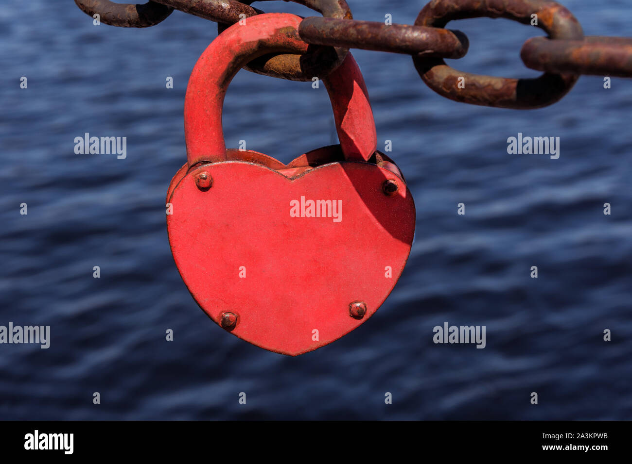 Amore cuore lucchetto della catena arrugginito sul blu del mare sullo sfondo dell'acqua. Amore forte concetto. Foto Stock