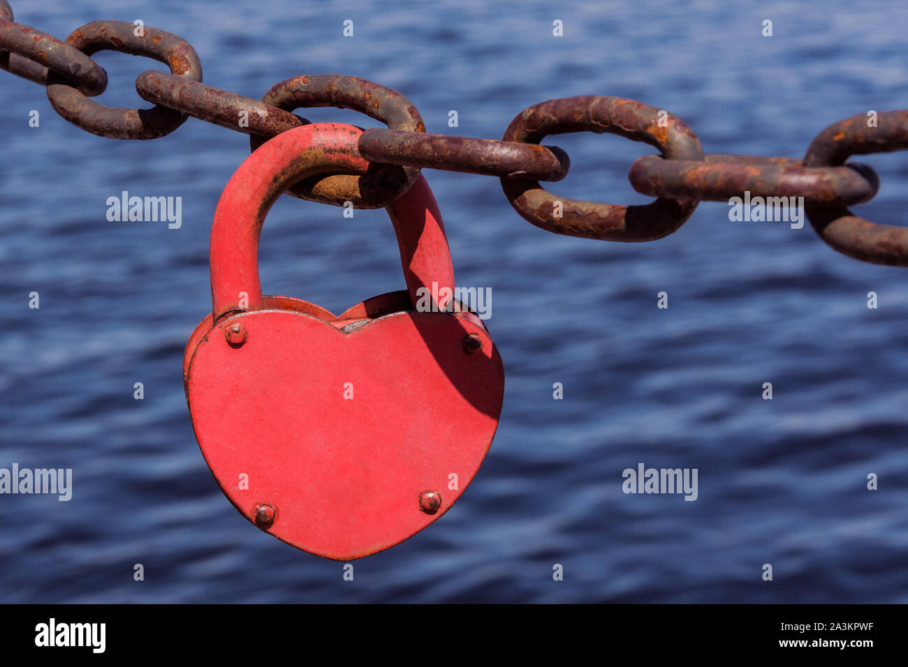 Amore cuore lucchetto della catena arrugginito sul blu del mare sullo sfondo dell'acqua. Amore forte concetto. Foto Stock