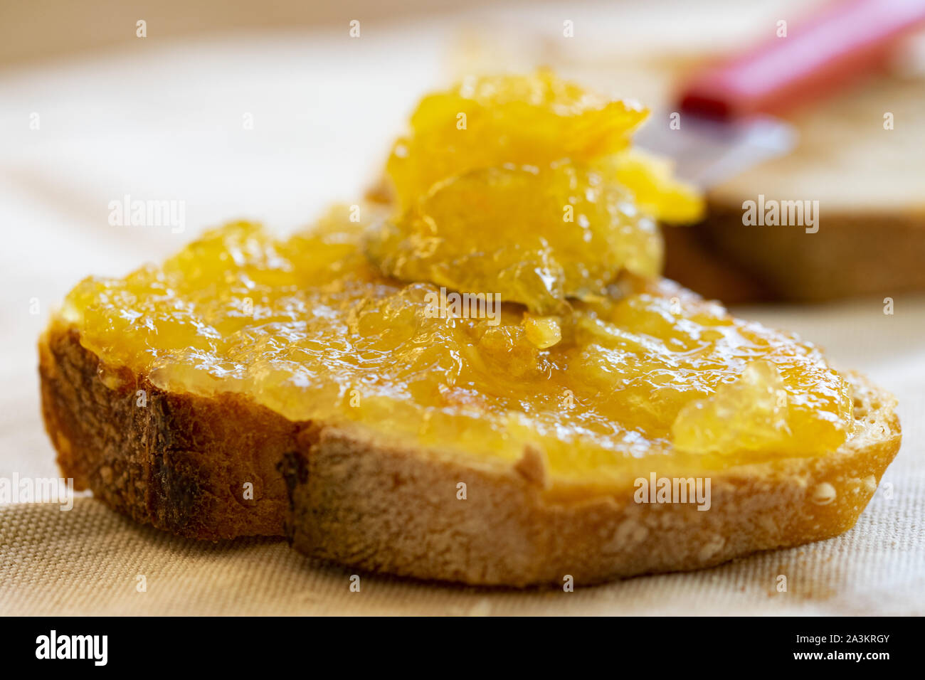 Diffusione di orange marmellata su una fetta di pane Foto Stock