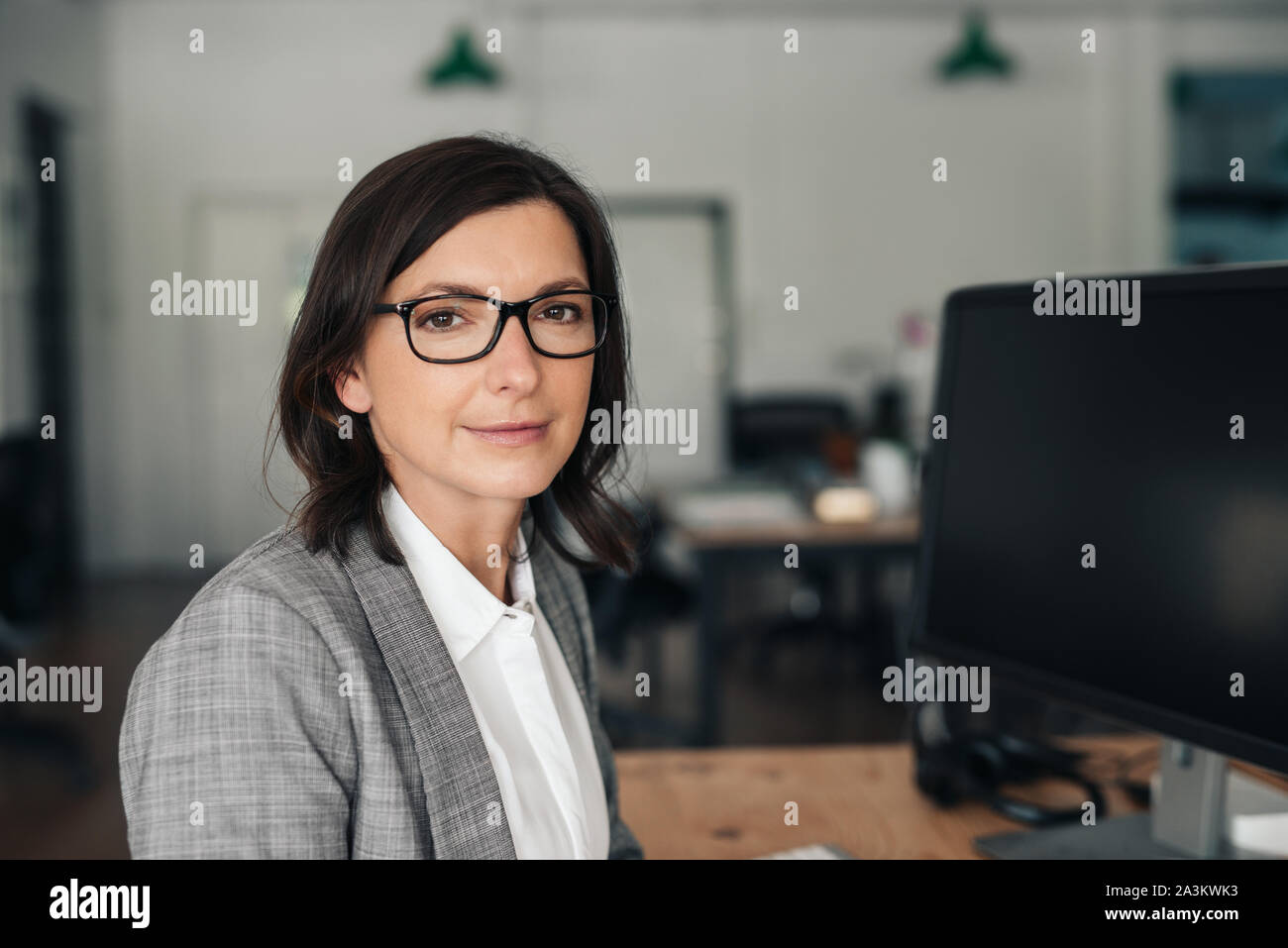 Imprenditrice sorridente seduto alla sua scrivania in un ufficio Foto Stock