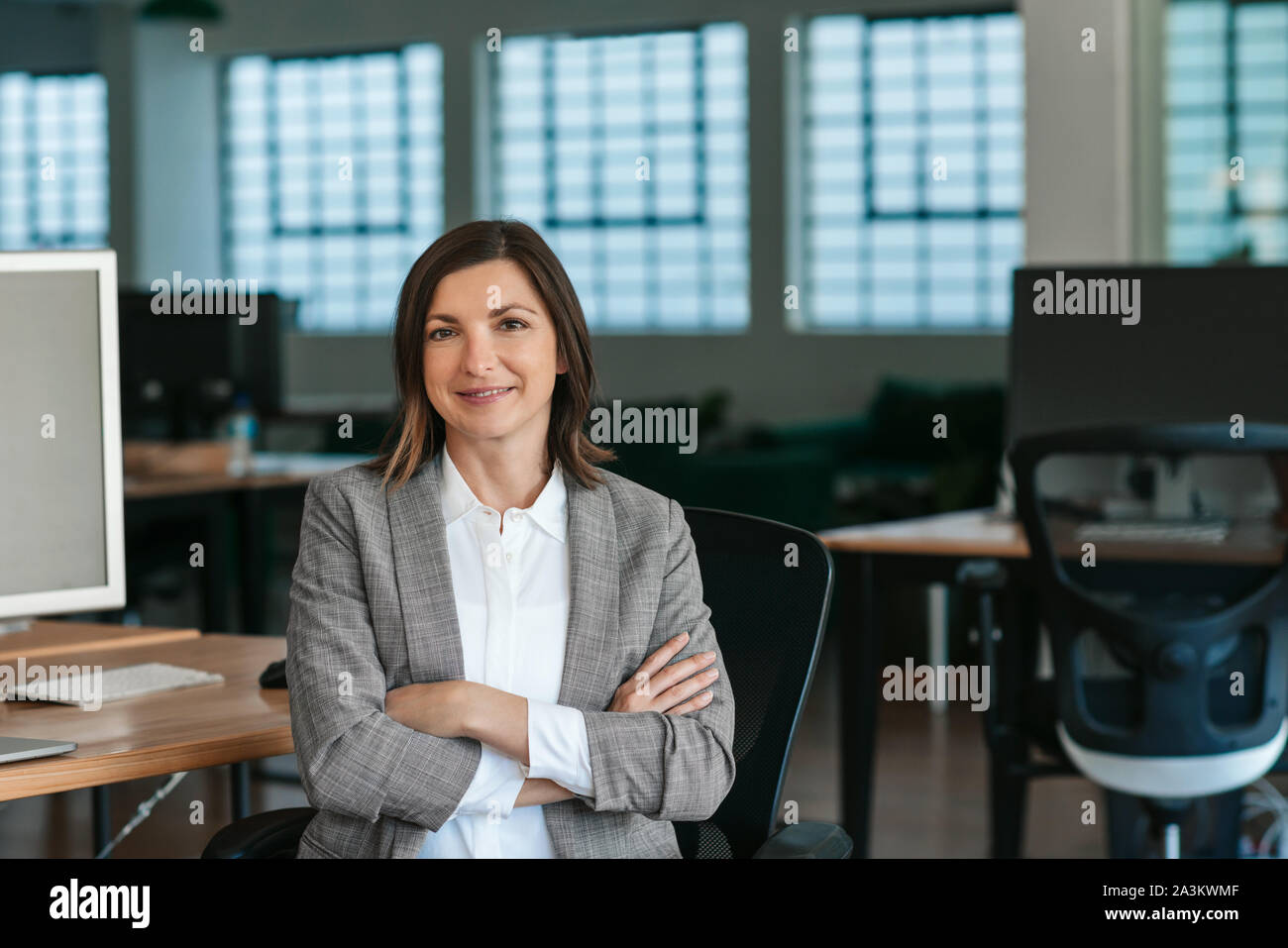 Imprenditrice sorridente seduto alla sua scrivania in ufficio nel pomeriggio Foto Stock
