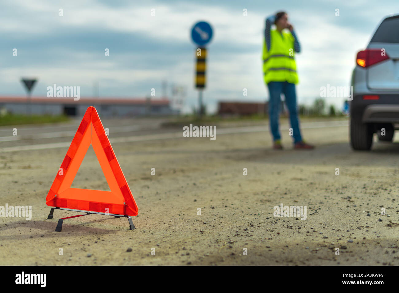 Ripartizione del veicolo e il triangolo di avvertenza sulla strada, donna usando il telefono per chiedere aiuto e assistenza stradale Foto Stock