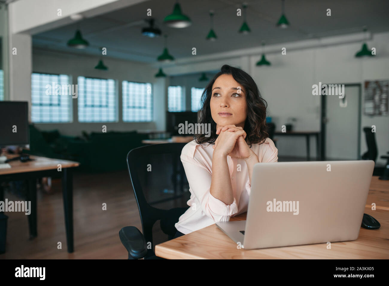 Giovane imprenditrice pensando a lavorare mentre è seduto alla sua scrivania Foto Stock