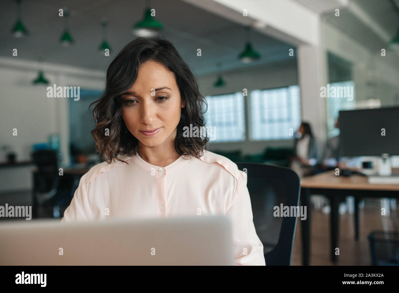 Sorridente giovane imprenditrice lavorando sul suo computer portatile in un ufficio Foto Stock