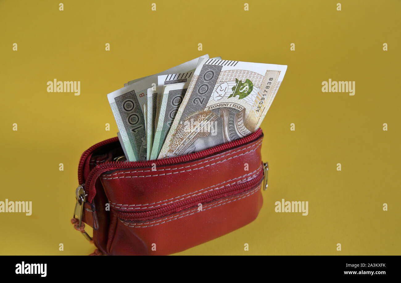 In pelle rossa / portafoglio portamonete opwn con banconote di 200 zloty polacco all'interno isolato su sfondo giallo vicino. Foto Stock