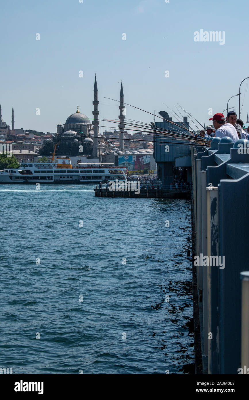 Istanbul: skyline della città e i pescatori locali con la loro canna da pesca sul Ponte di Galata, il ponte che attraversa il Golden Horn e il Bosforo Foto Stock