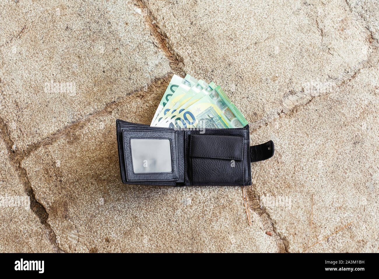 Perso il nero portafoglio in pelle con denaro euro sulla strada. Un centesimo di banconote all'interno di esso Foto Stock
