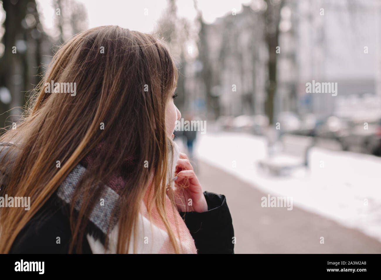 Giovane donna di indossare abiti caldi in piedi su una strada di città in inverno Foto Stock
