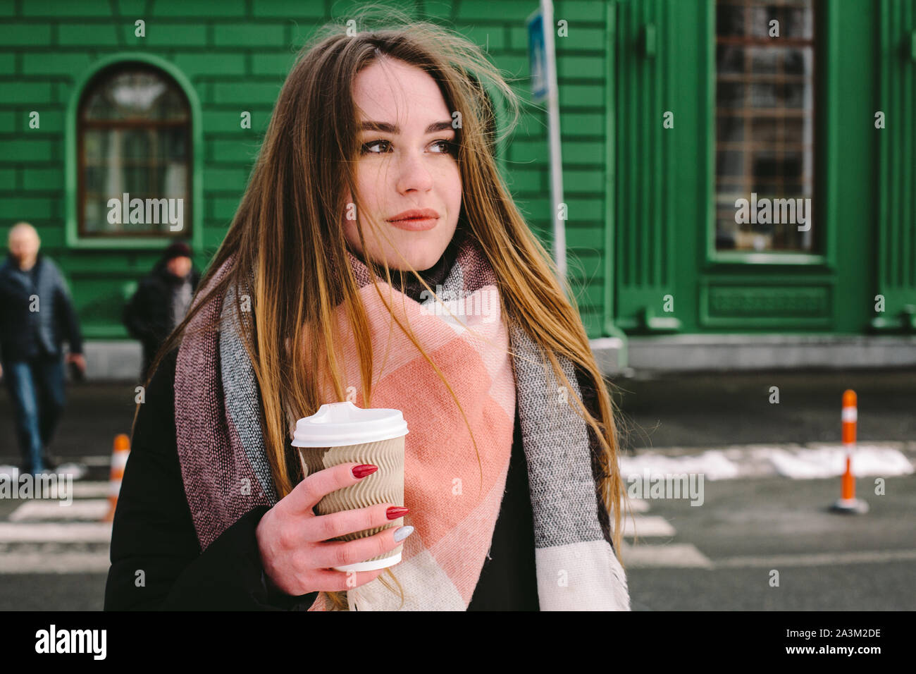 Triste giovane donna in abiti caldi in piedi in strada di città in inverno Foto Stock