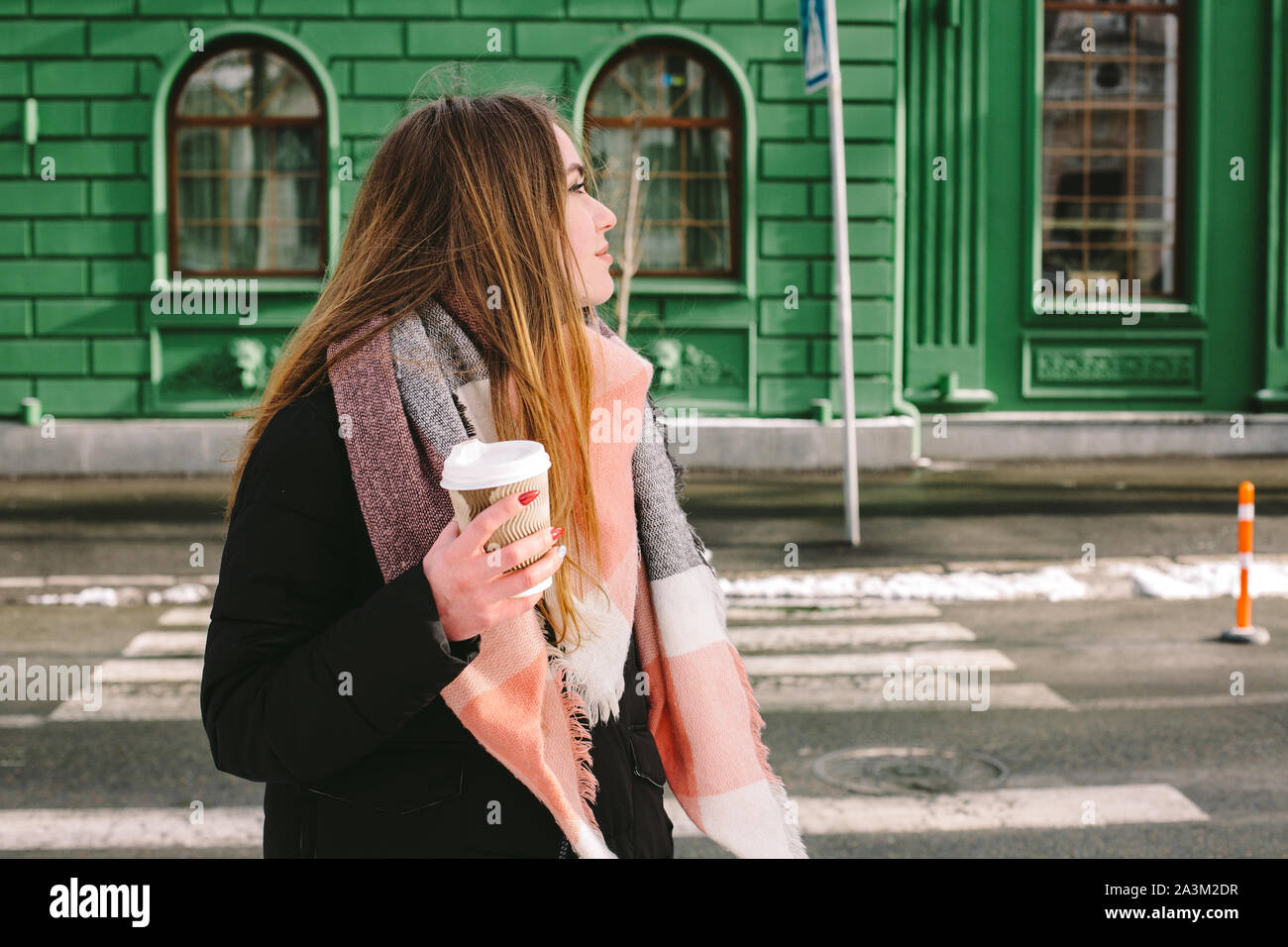 Triste giovane donna in abiti caldi in piedi in strada di città in inverno Foto Stock