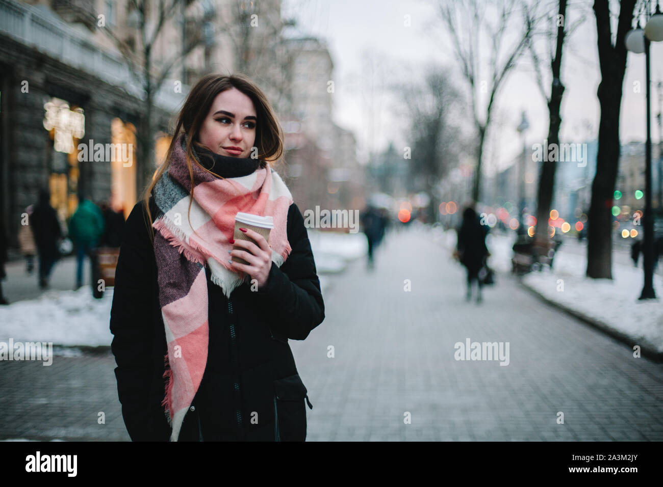 Triste giovane donna che indossa abiti caldi a camminare sulla via della città durante il periodo invernale Foto Stock