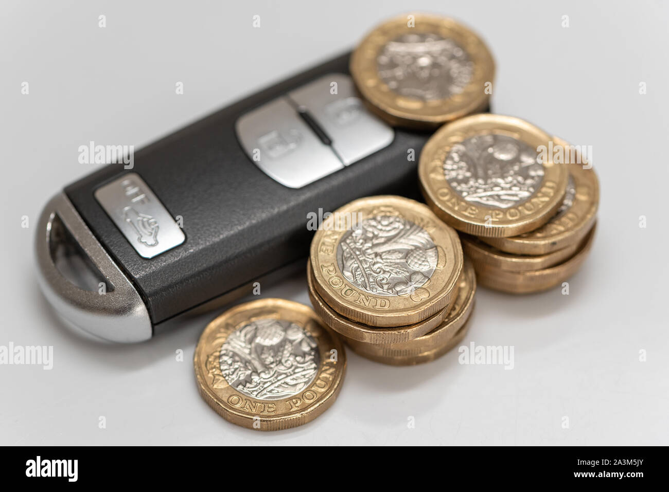 Una moderna auto del tasto del telecomando dalla pila di UK pound delle monete in euro - un concetto per auto costa, prestiti, assicurazioni o expsenses Foto Stock