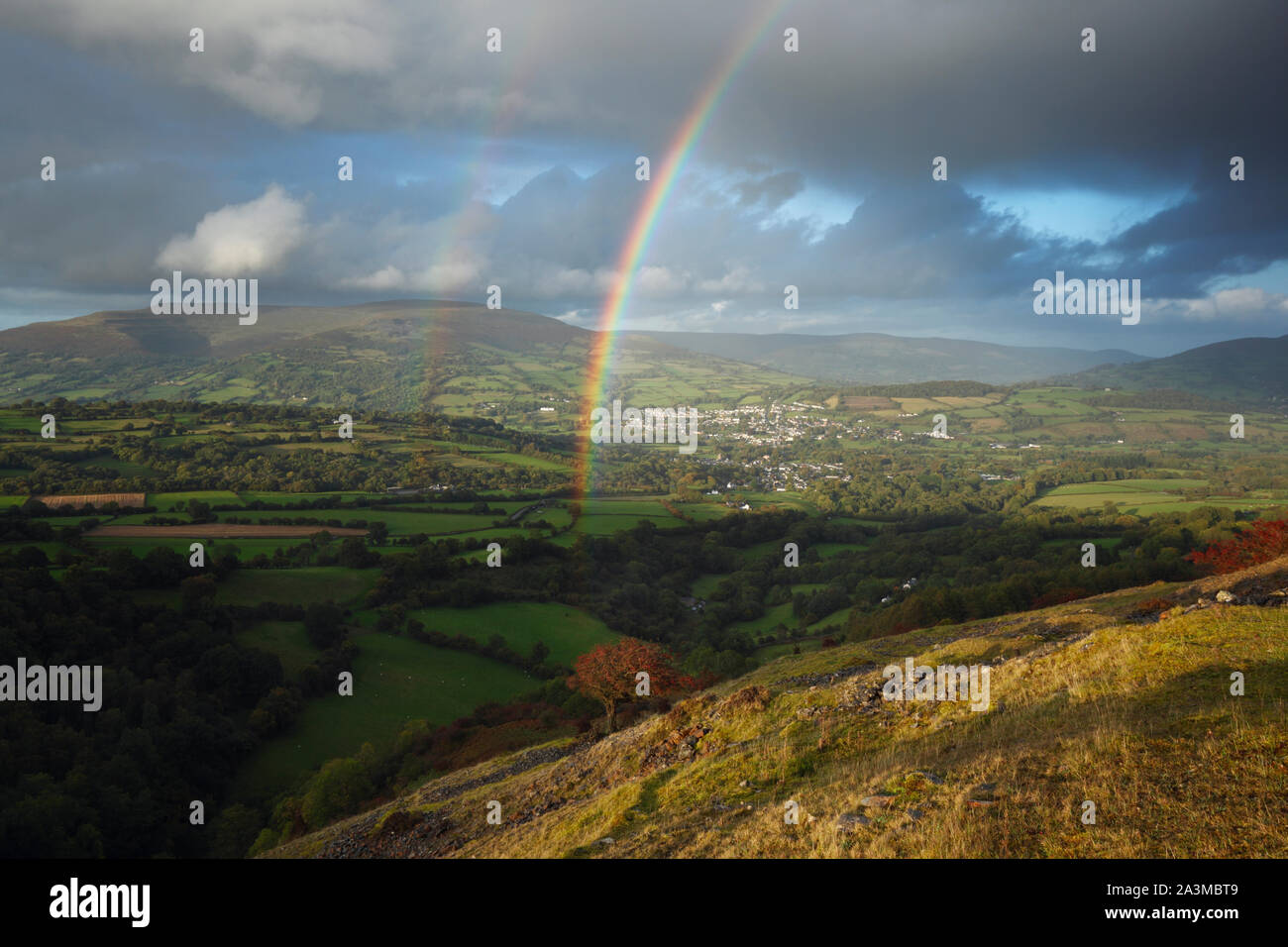 Rainbows oltre Crickhowell con il nero montagne in distanza. Parco Nazionale di Brecon Beacons. La contea di Powys. Il Galles. Regno Unito. Ottobre 2019 Foto Stock