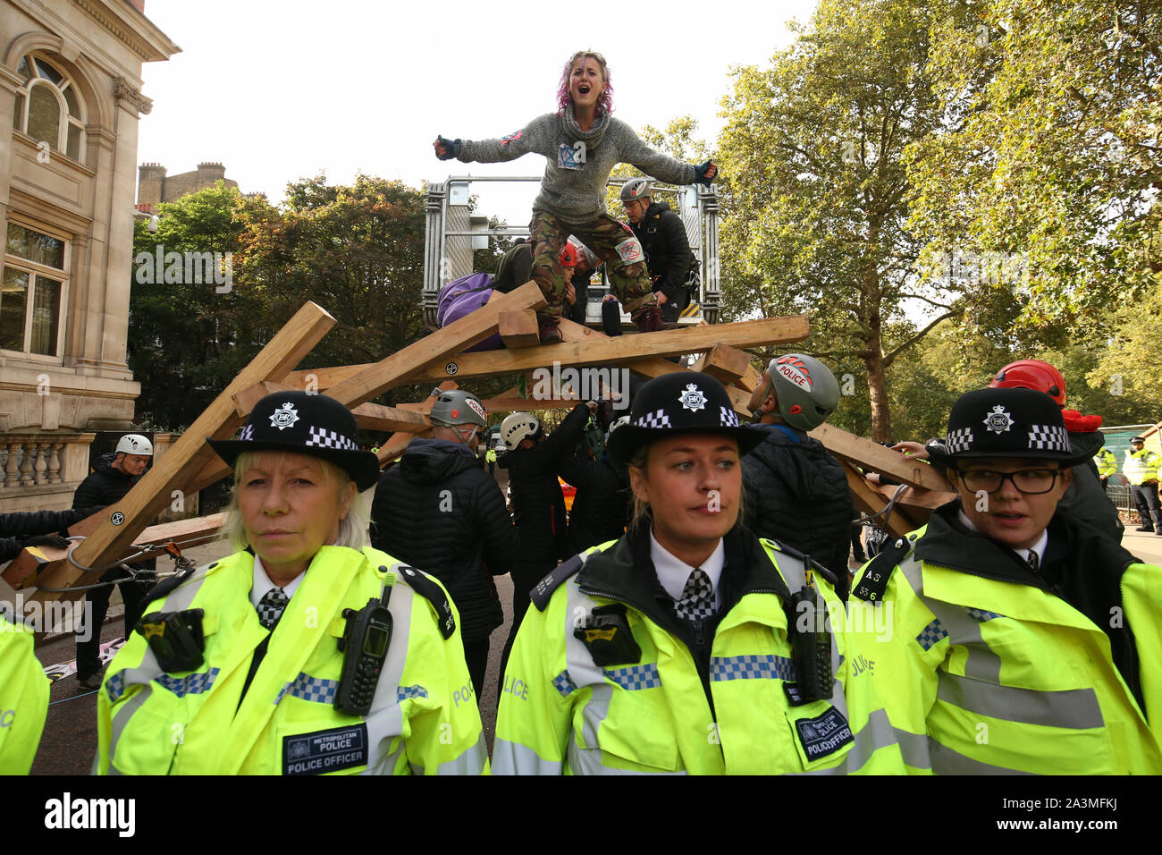 La polizia circonda i manifestanti sulla parte superiore di una struttura in legno su Birdcage a piedi durante il terzo giorno di una ribellione di estinzione (XR) protesta in Westminster, Londra. Foto Stock