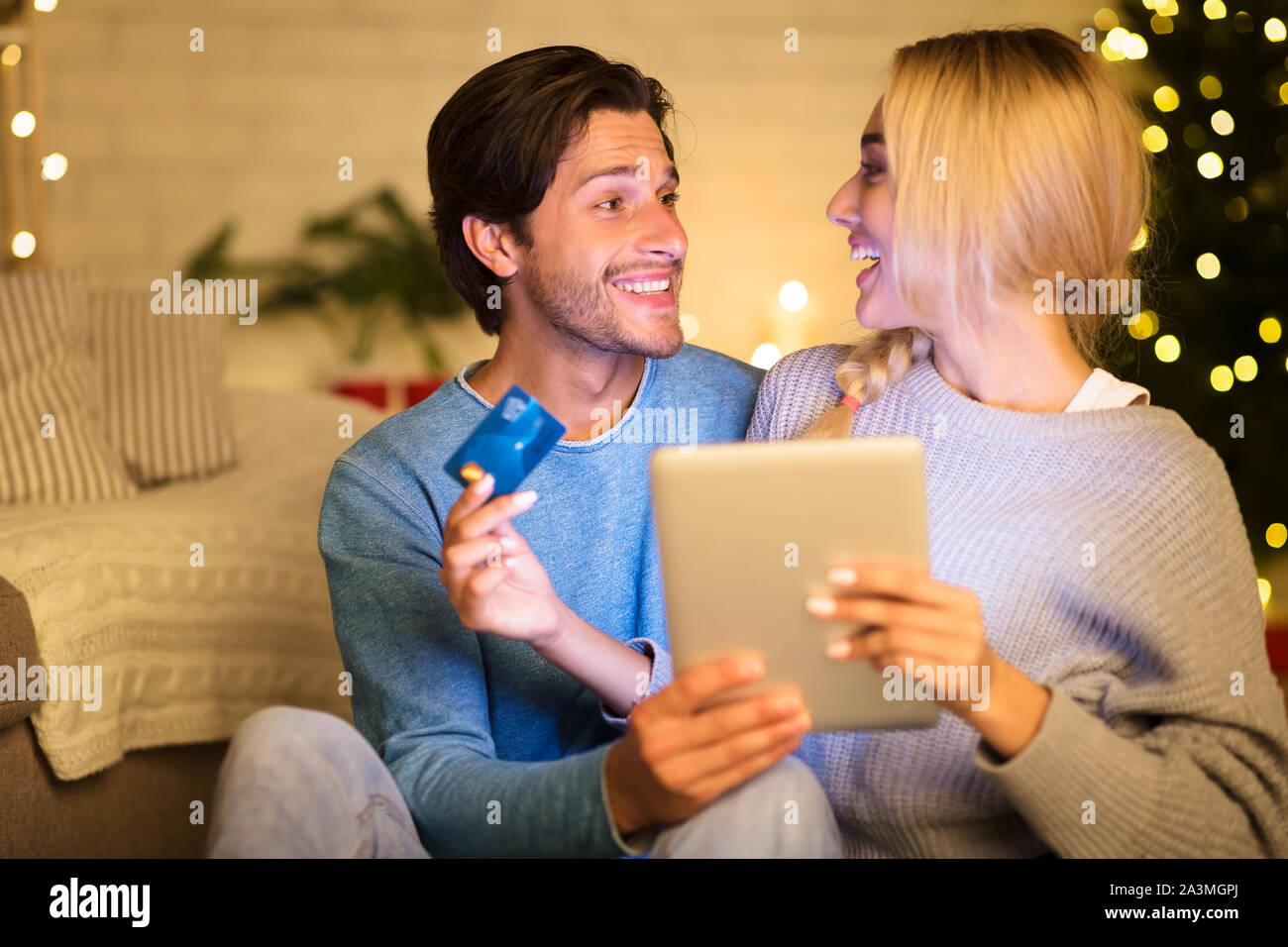 Giovane comprare regali di Natale online utilizzando tavoletta digitale Foto Stock