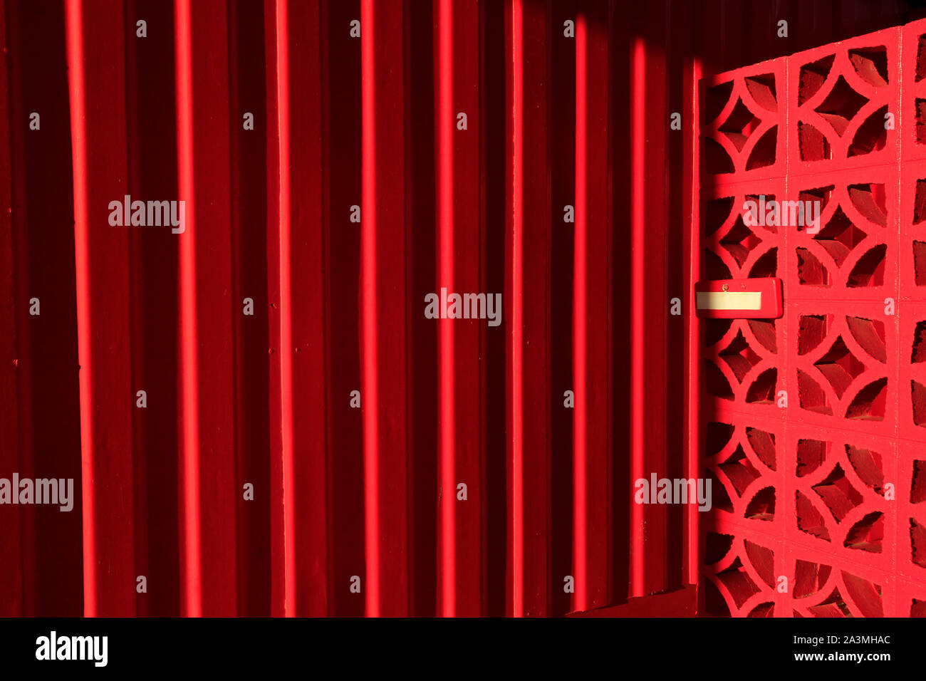 Rosso brillante dipinto di un muro di mattoni Foto Stock