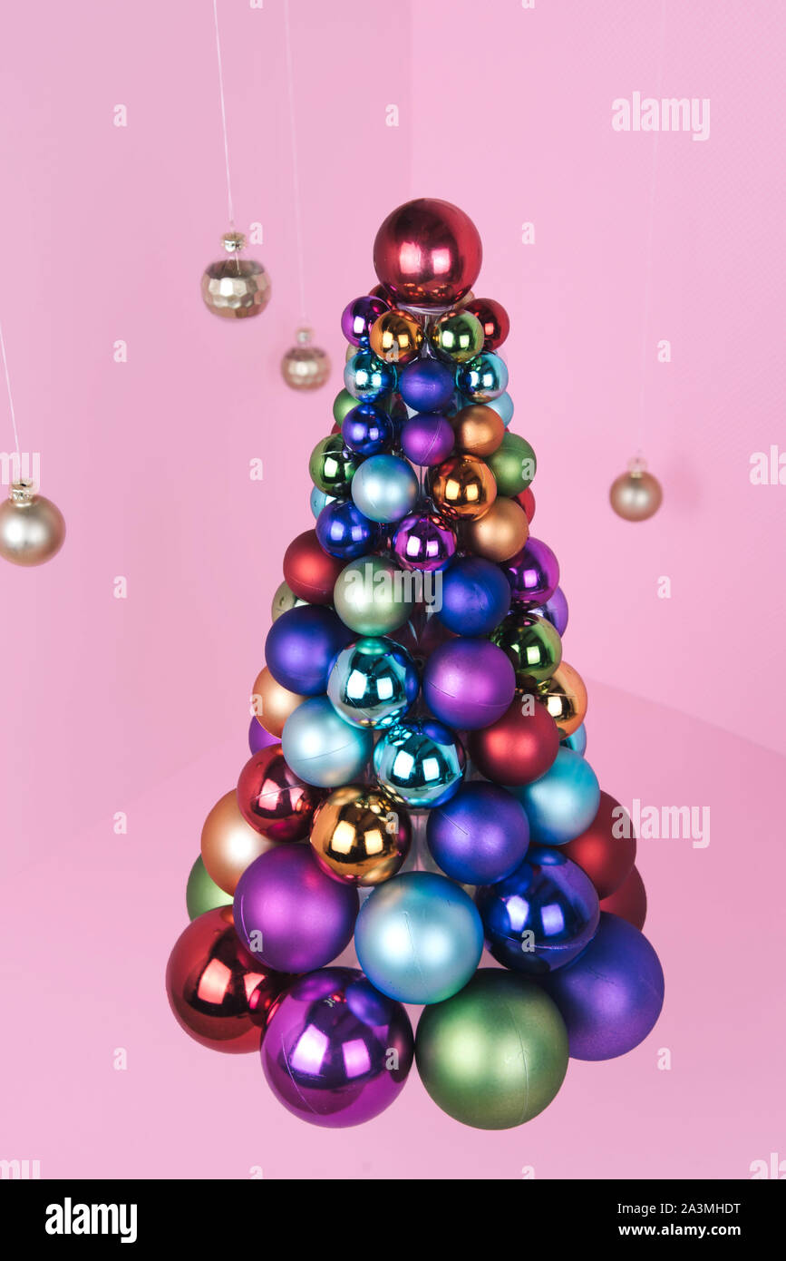 Albero di Natale fatto di decorazione a sfera su sfondo rosa. Foto Stock