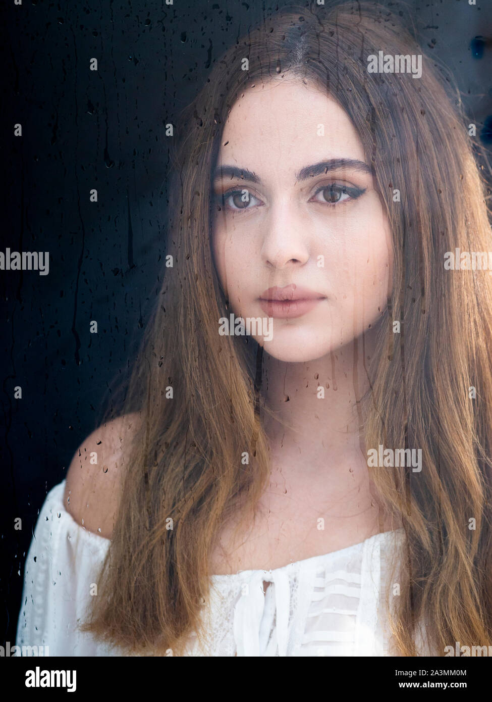 Bellissima giovane donna georgiana dietro vetro bagnato Foto Stock