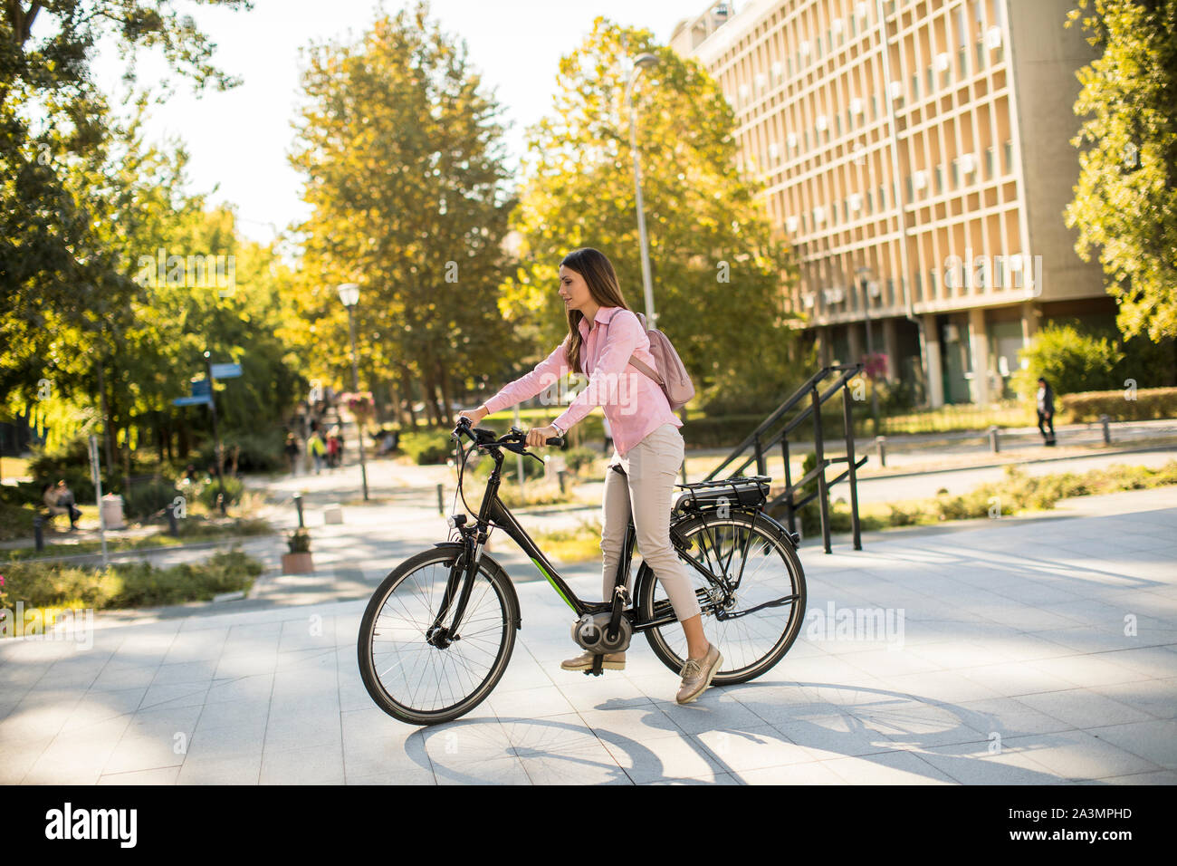 Giovane donna in sella ad una bicicletta elettrica in ambiente urbano Foto Stock
