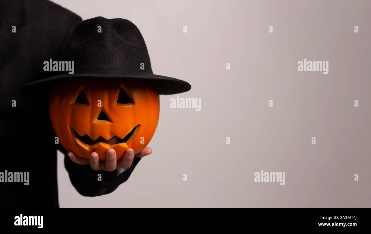 Tagliare la zucca faccia mettere sul cappello nero e cercando seriamente Foto Stock