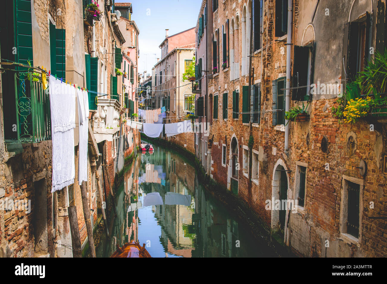 Romantischer Kanal in Venedig, rustikale Häusermauern mit Wäscheleine und Blunmen Foto Stock