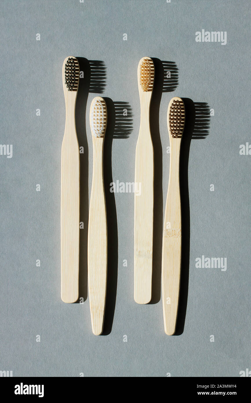 Quattro eco-friendly bamboo spazzolini da denti su un minimalista sfondo grigio. Zero rifiuti Nozione di plastica libera, organico, eco-friendly shopping Foto Stock