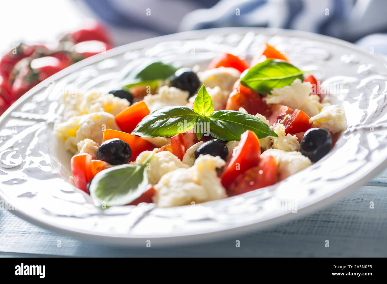 Insalata caprese con mozzarella pomodori freschi olive e le foglie di basilico. Italiano o mediterraneo pasto sano Foto Stock