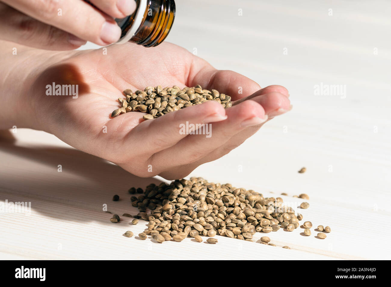 Mano con semi di cannabis e bottiglia di medicina, medicina concetto da sementi di canapa e semi di marijuana con spazio di copia Foto Stock