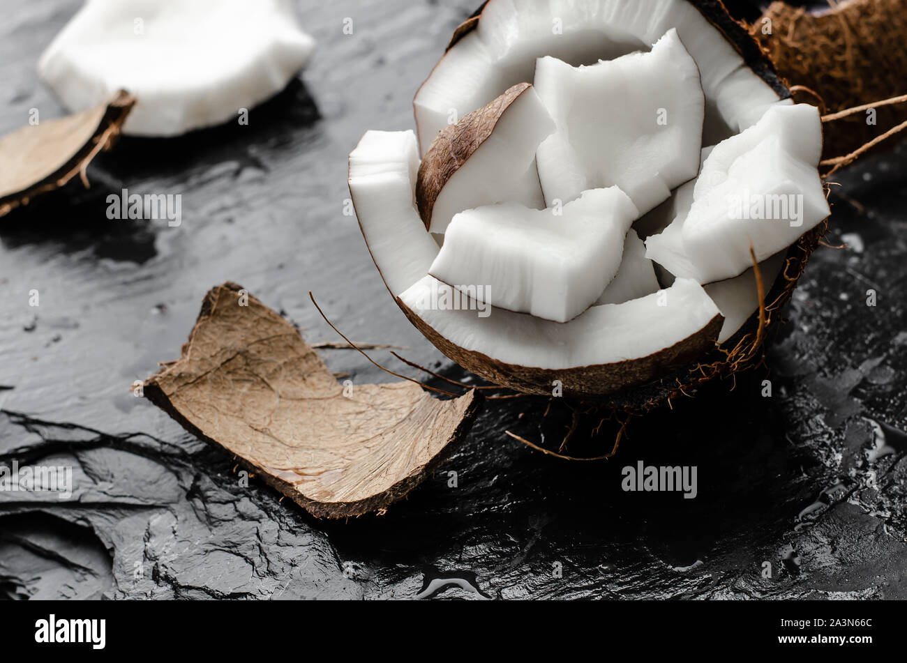 Cocco hlf con pezzi su ardesia nera sullo sfondo di pietra. Alta sano cibi grassi concetto. Foto Stock