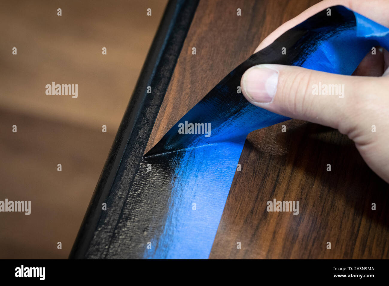 Rimuovere a mano blu del pittore del nastro dal bordo di mobili rifiniti paint job. Foto Stock