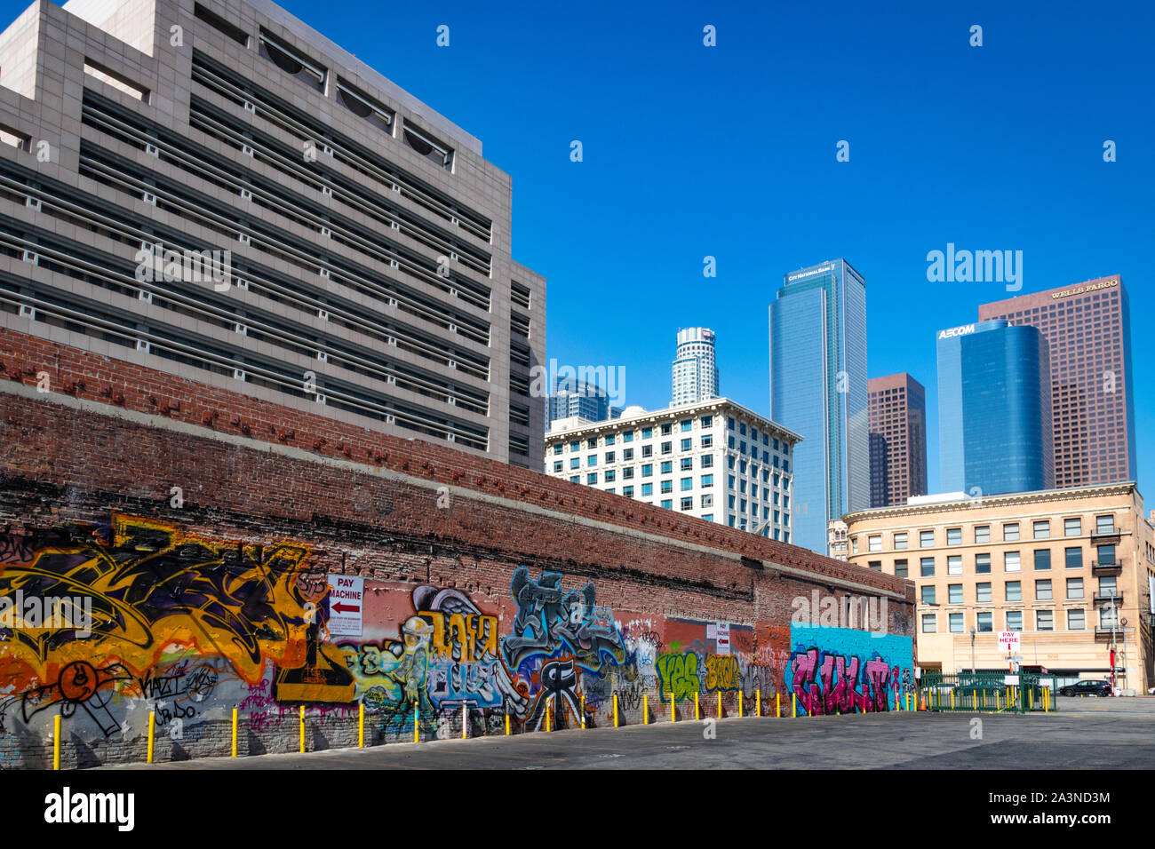 Vista soleggiata del centro di Los Angeles, California; graffiti di Street art nel parcheggio vuoto con skyline di Los Angeles in lontananza Foto Stock