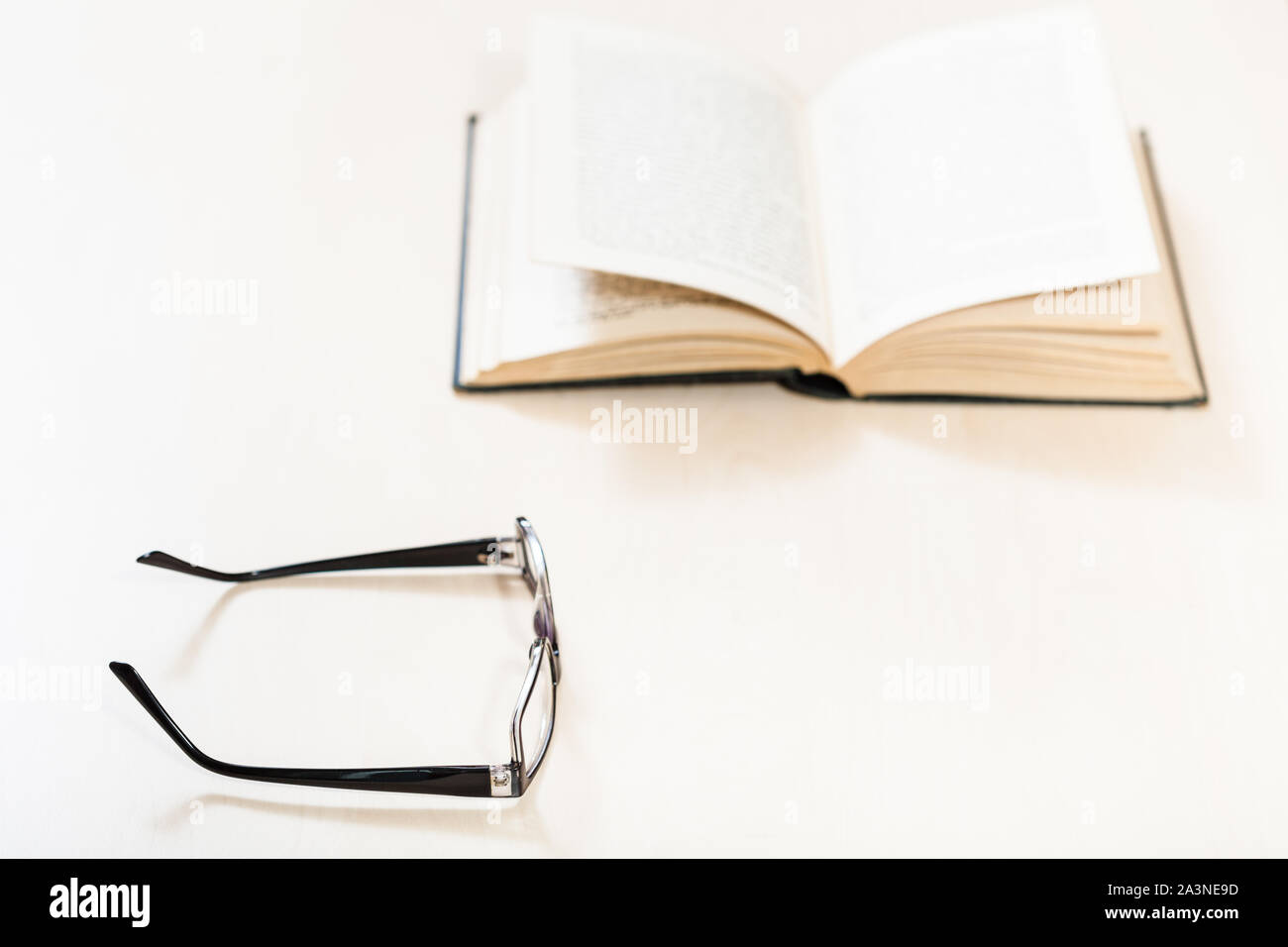 Libro di lettura con low vision - occhiali e libro aperto sulla tavola di pallido (messa a fuoco in primo piano) Foto Stock