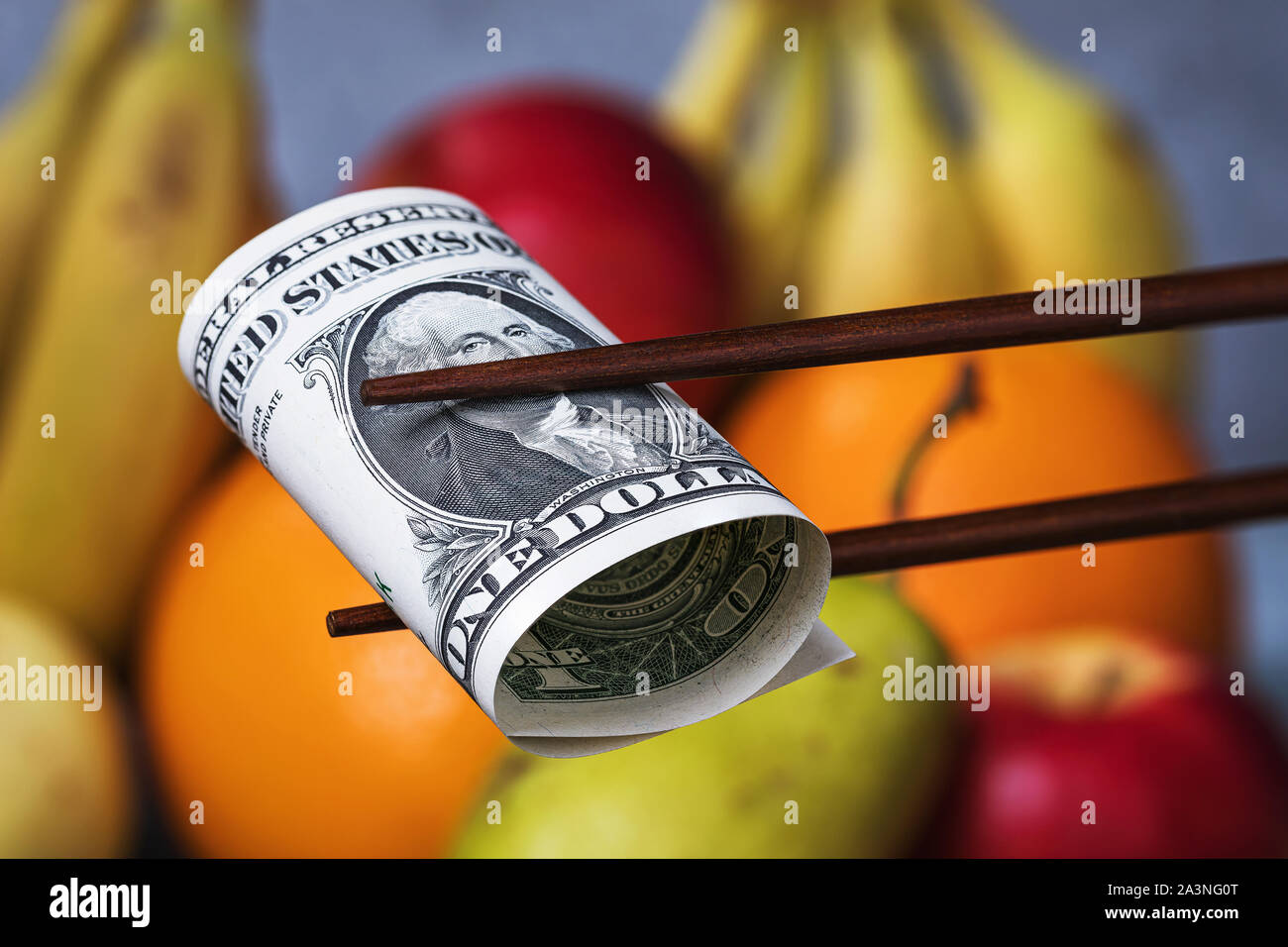 Bastoncini cinesi detengono un dollaro su uno sfondo di frutta. Concetto sul tema del confronto economico tra Stati Uniti e Cina. Embargo alimentare Foto Stock