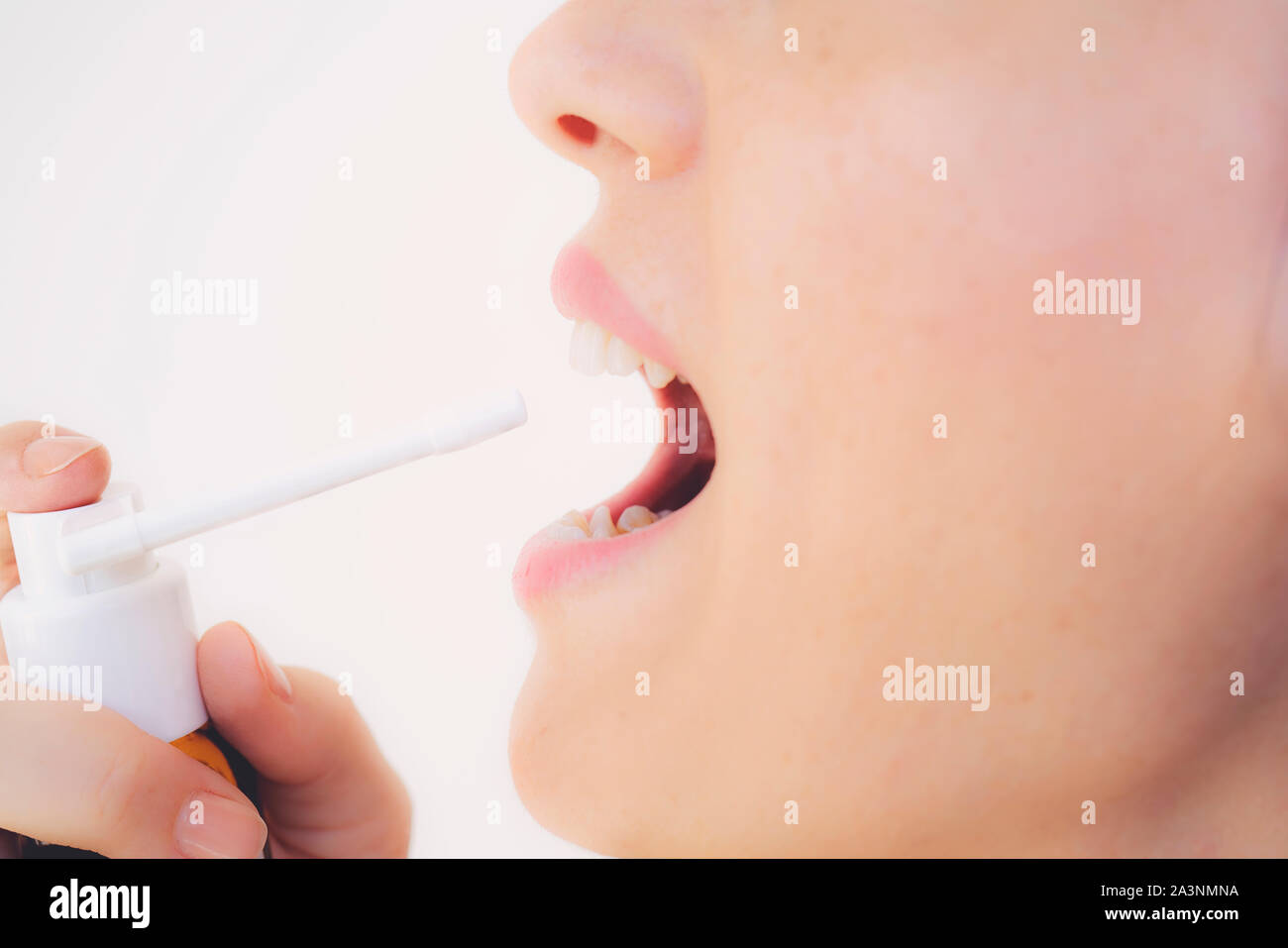 Spray per il mal di gola. Foto di una donna che considera la sua gola con uno spray e spruzza nella sua bocca. Il concetto di salute e malattia. Foto Stock