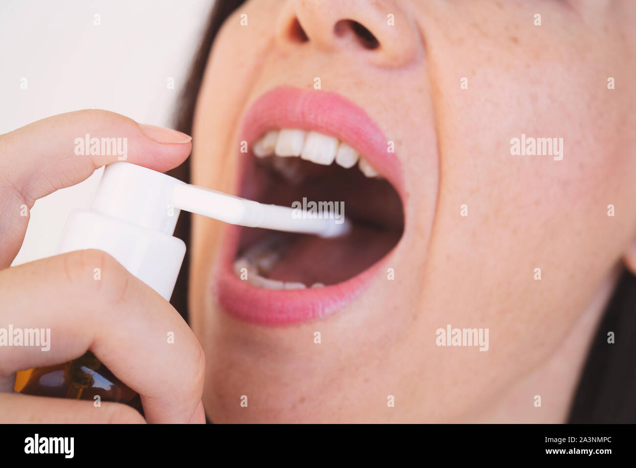 Spray per il mal di gola. Foto di una donna che considera la sua gola con uno spray e spruzza nella sua bocca. Il concetto di salute e malattia. Foto Stock