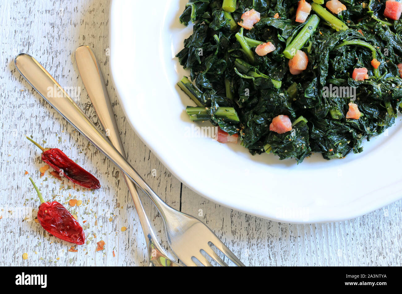 Concetto di cucina italiana. Bruschette con cavolo nero e la pancetta su un tavolo di legno. Rustico italiano piatto laterale Foto Stock