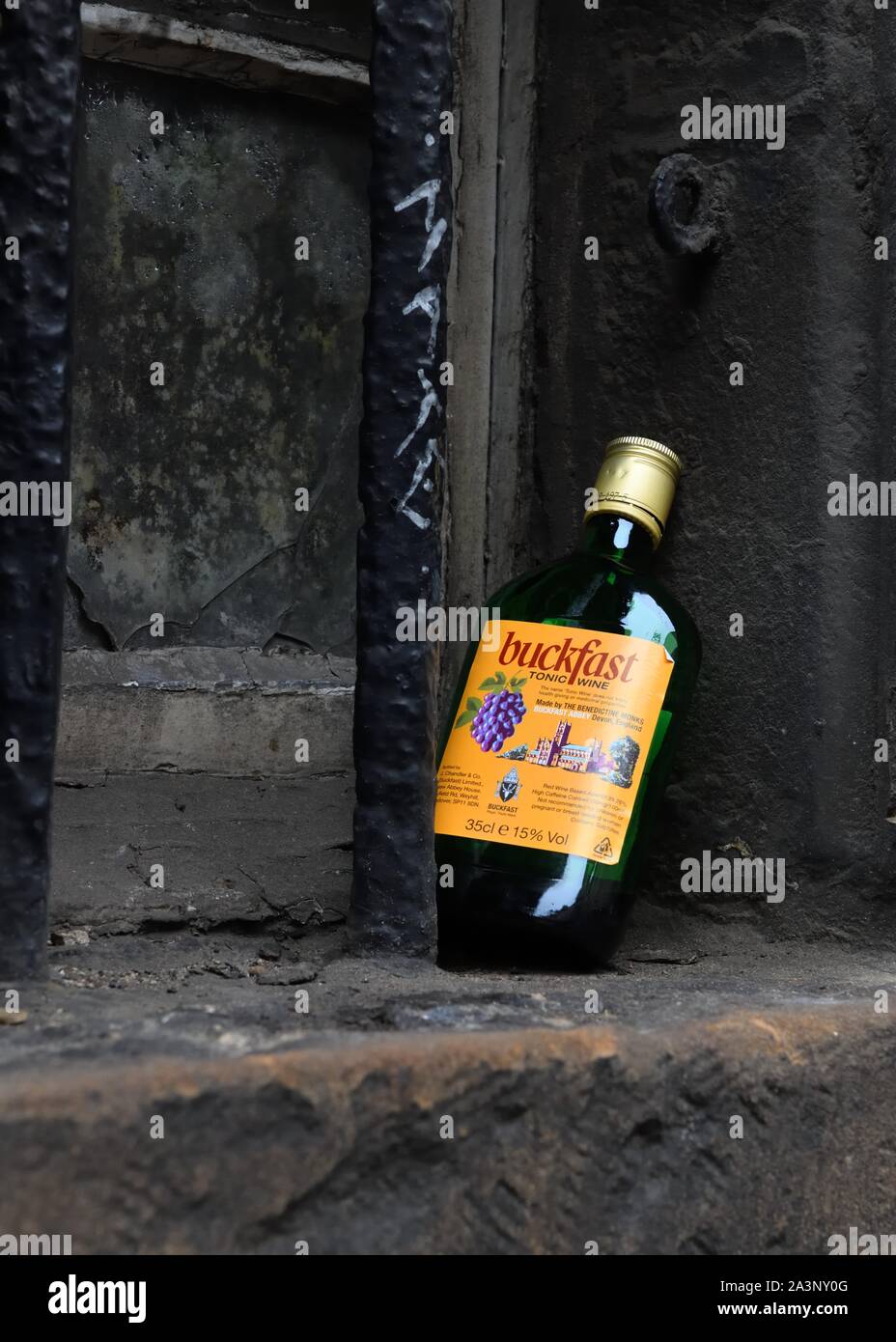 Un vuoto di mezza bottiglia di buon mercato Buckfast vino puntellato su una vecchia finestra sporca listello in Edimburgo, Scozia, Regno Unito, Europa Foto Stock