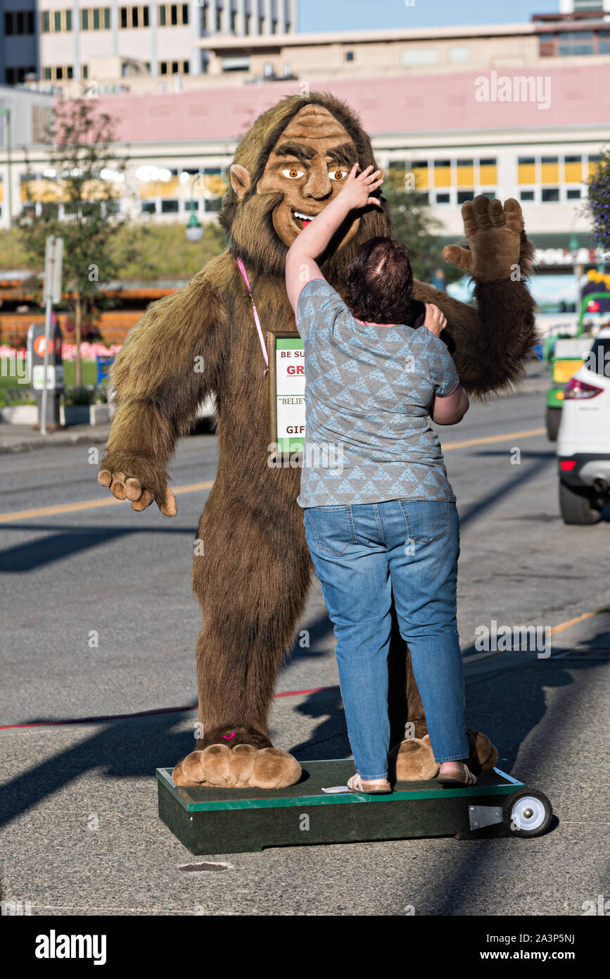 Un lavoratore regola un gigante farcita Bigfoot o Sasquatch per attrarre turisti in un negozio lungo la quarta Avenue nel centro cittadino di Anchorage in Alaska,. Foto Stock