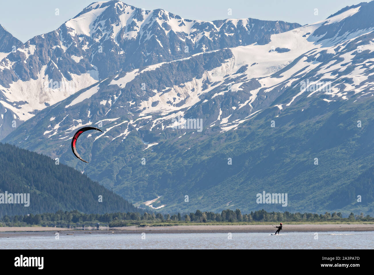 Un kite surfer passa di montagne innevate su 20 miglia di fiume vicino a Portage, Alaska. Foto Stock