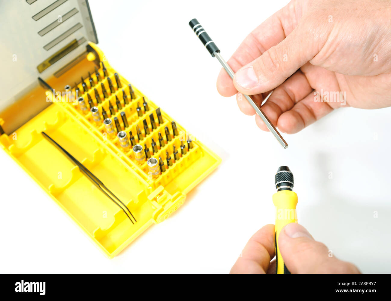 Mani dell'uomo è in possesso di parti di un cacciavite collassabile. Sullo sfondo vi è un insieme di bit. Foto Stock