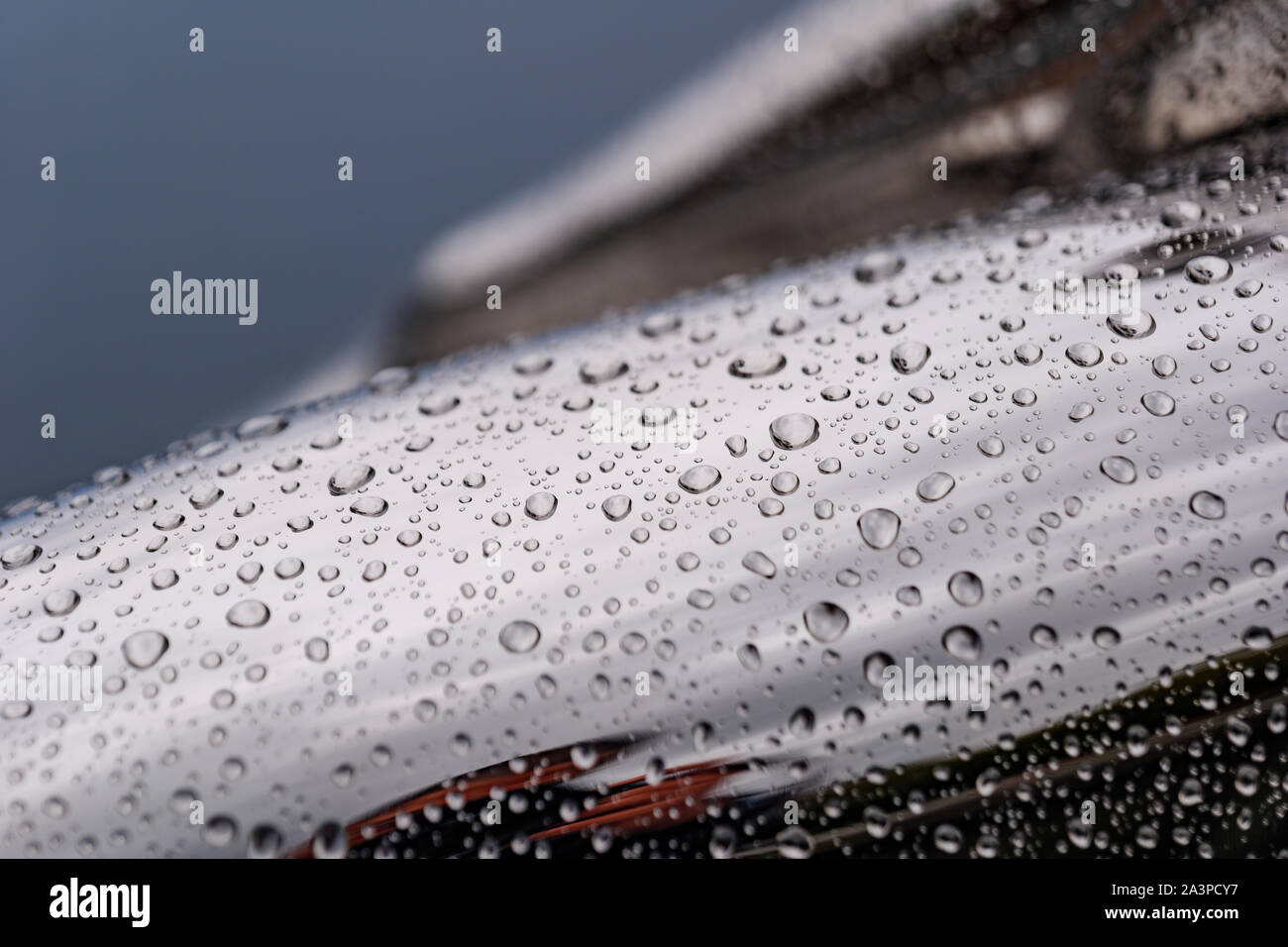 Close up e vista macro di pioggia di gocce di acqua su lucido curvatura levigata la superficie cromata di scultura astratta. Foto Stock