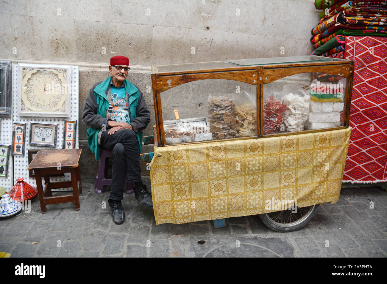 Un anziano commerciante alimentare di dolciumi, halwa e la pasticceria seduto alla sua pressione di stallo nel mercato della Kasbah, nella Medina di Tunisi, Tunisia. Foto Stock