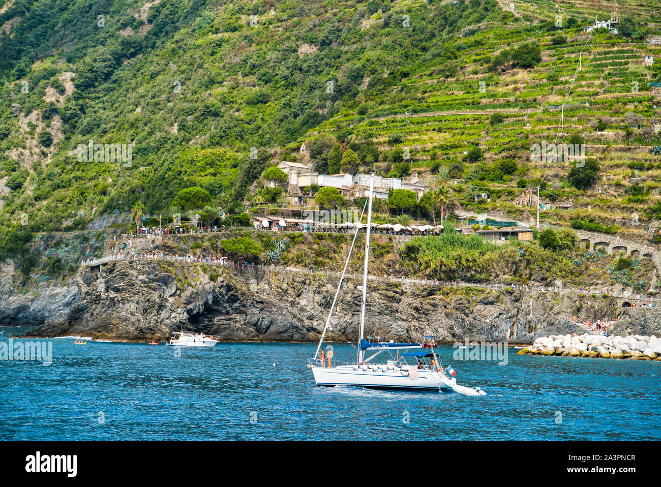 Manarola, Liguria, Italia - Agosto 17, 2019: un bianco di neve, yacht al largo delle coste del Mar Ligure. Costa rocciosa Foto Stock