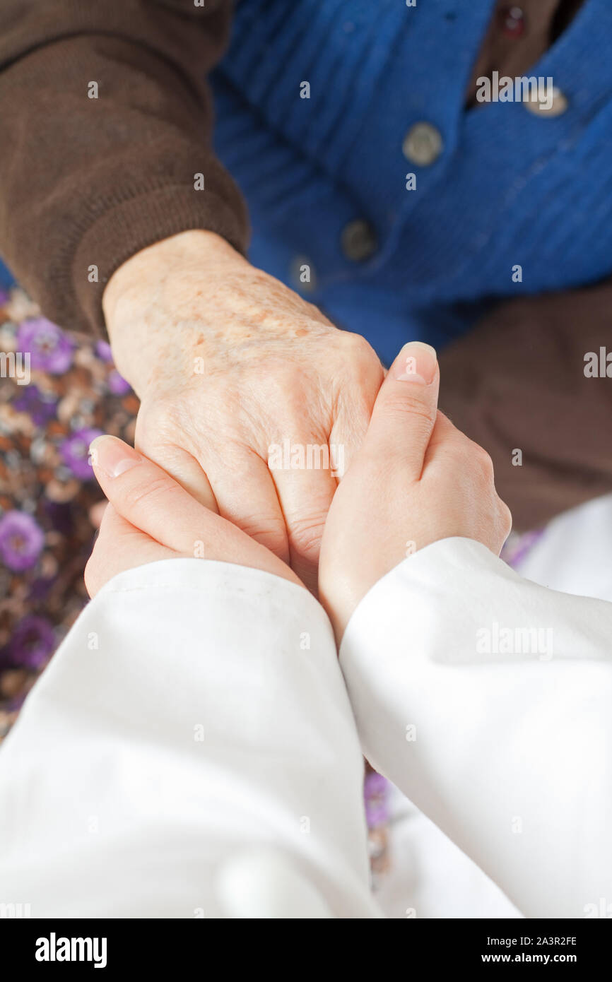 Giovane medico mantiene la vecchia donna la mano Foto Stock