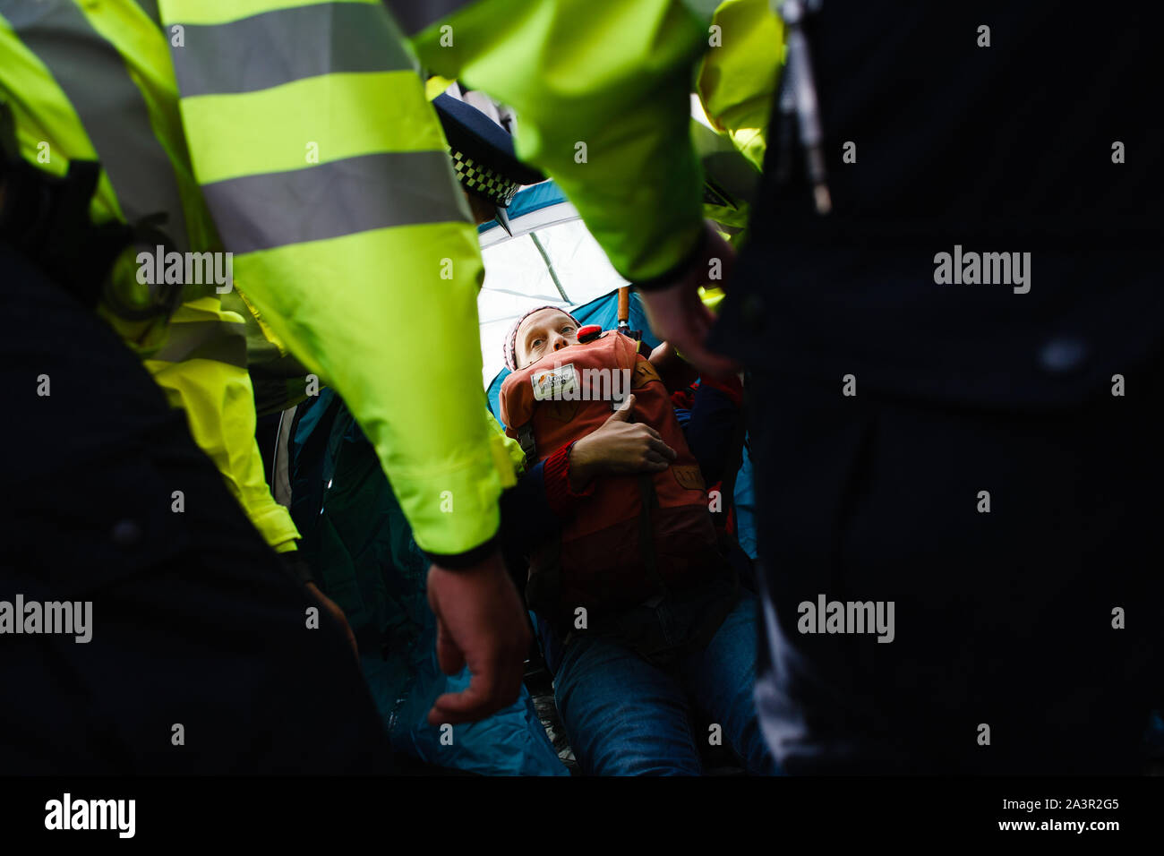 Gli ufficiali di polizia prepararsi ad arrestare un membro del cambiamento climatico movimento attivista ribellione di estinzione (XR) rifiuta di passare da un accampamento su Victoria Street durante il terzo giorno del gruppo 'International Rebellion' a Londra.gli ufficiali di polizia continuano a cancellare i dimostranti e tende dai siti in Westminster, con attivisti che è stato messo in guardia circa il passaggio a una protesta designata area attorno a Nelson la colonna in Trafalgar Square o arresto volto. Blocchi simili dalla ribellione di estinzione in aprile, in corrispondenza di siti quali Oxford Circus e Waterloo Bridge, visto più di mille arrestati, una TAC Foto Stock