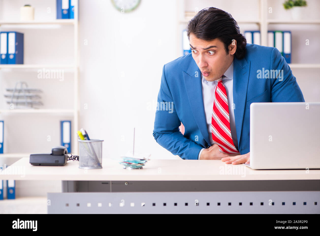 Il giovane maschio sofferenza dei dipendenti in ufficio Foto Stock