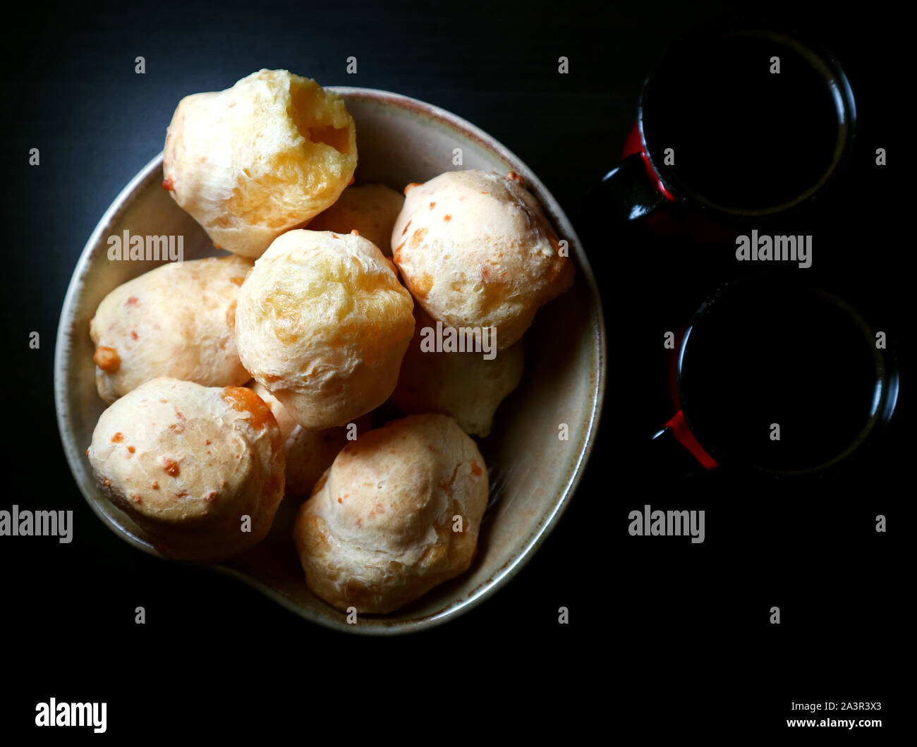 Brasiliano Ciambelle col formaggio. Pane al formaggio. Pao de Queijo e caffè. Sfondo scuro in stile d'arte. Tasto basso fotografia. Foto Stock