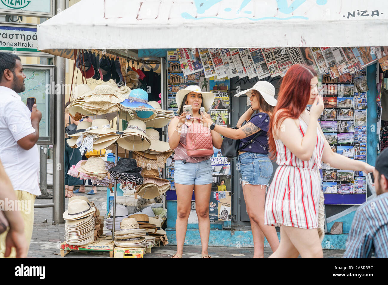 Atene GRECIA - Luglio 15 2019; due giovani donne provare cappelli e scattare foto con i telefoni cellulari nel quartiere Plaka in città. Foto Stock