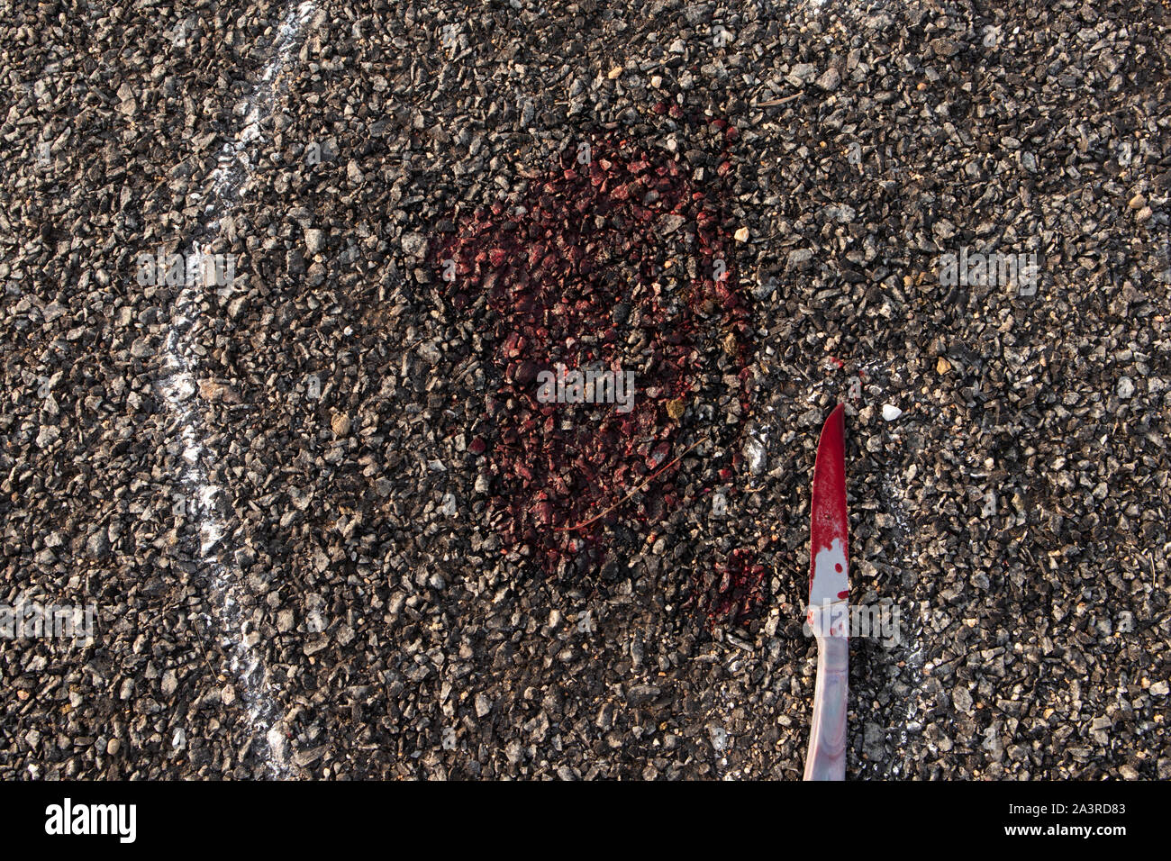 Close up della scena del crimine chalk outline vittima del corpo morto sulla strada con il coltello insanguinato e sangue su strada Foto Stock