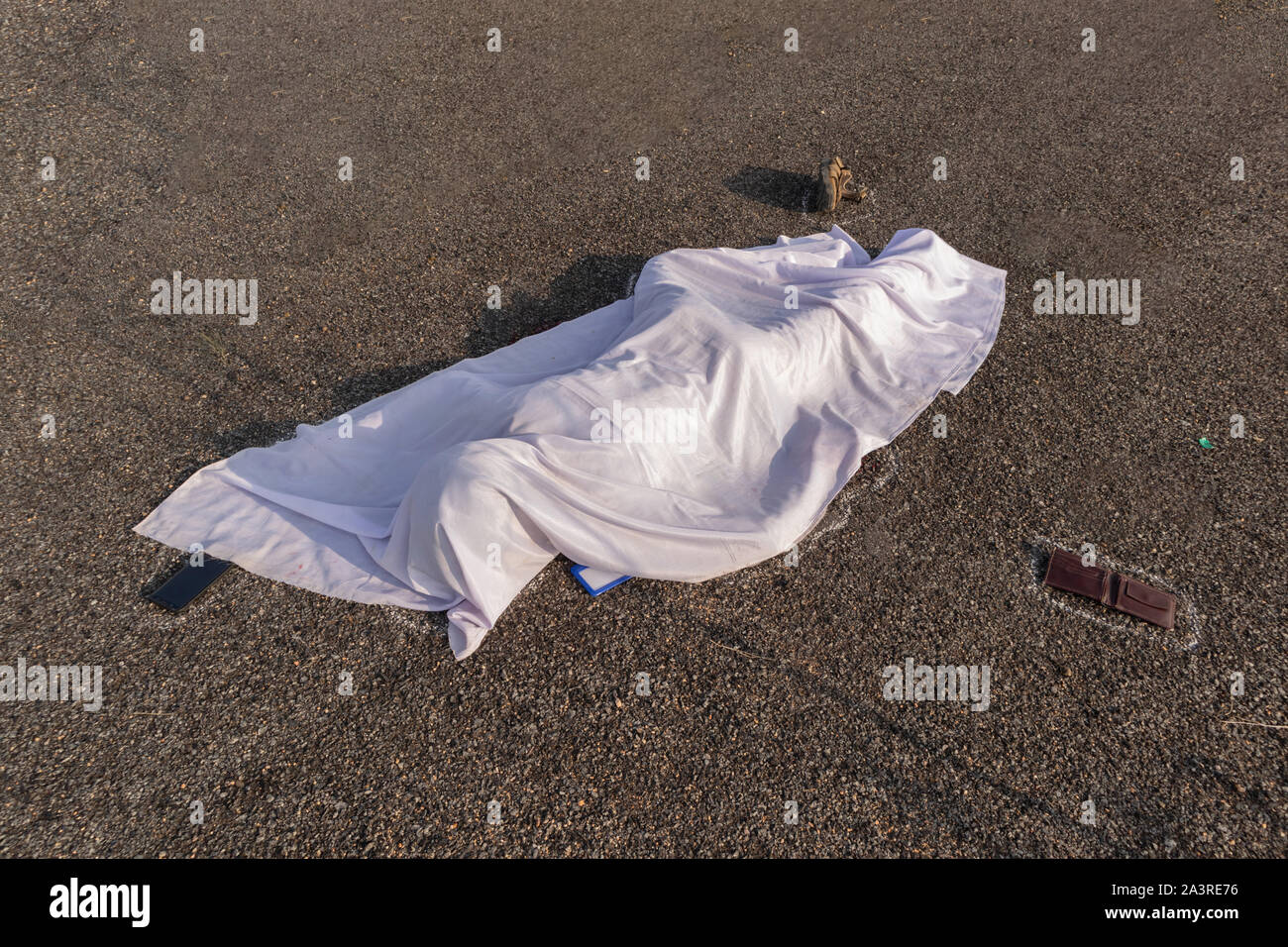 Concetto di incidente stradale scena, ad alto angolo di visione di chalk delineato corpo morto coperto da un panno bianco recante sulla strada Foto Stock